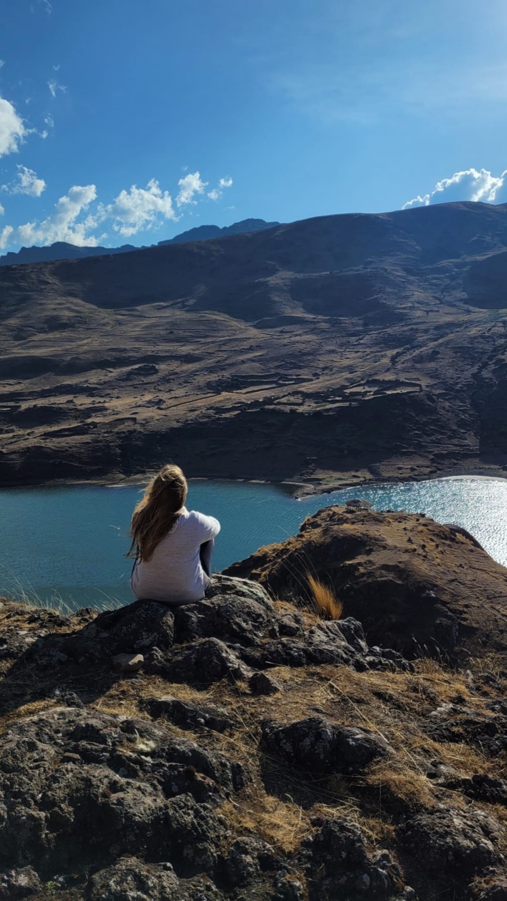 Jade sitting on a rock above a mountain lake in Peru