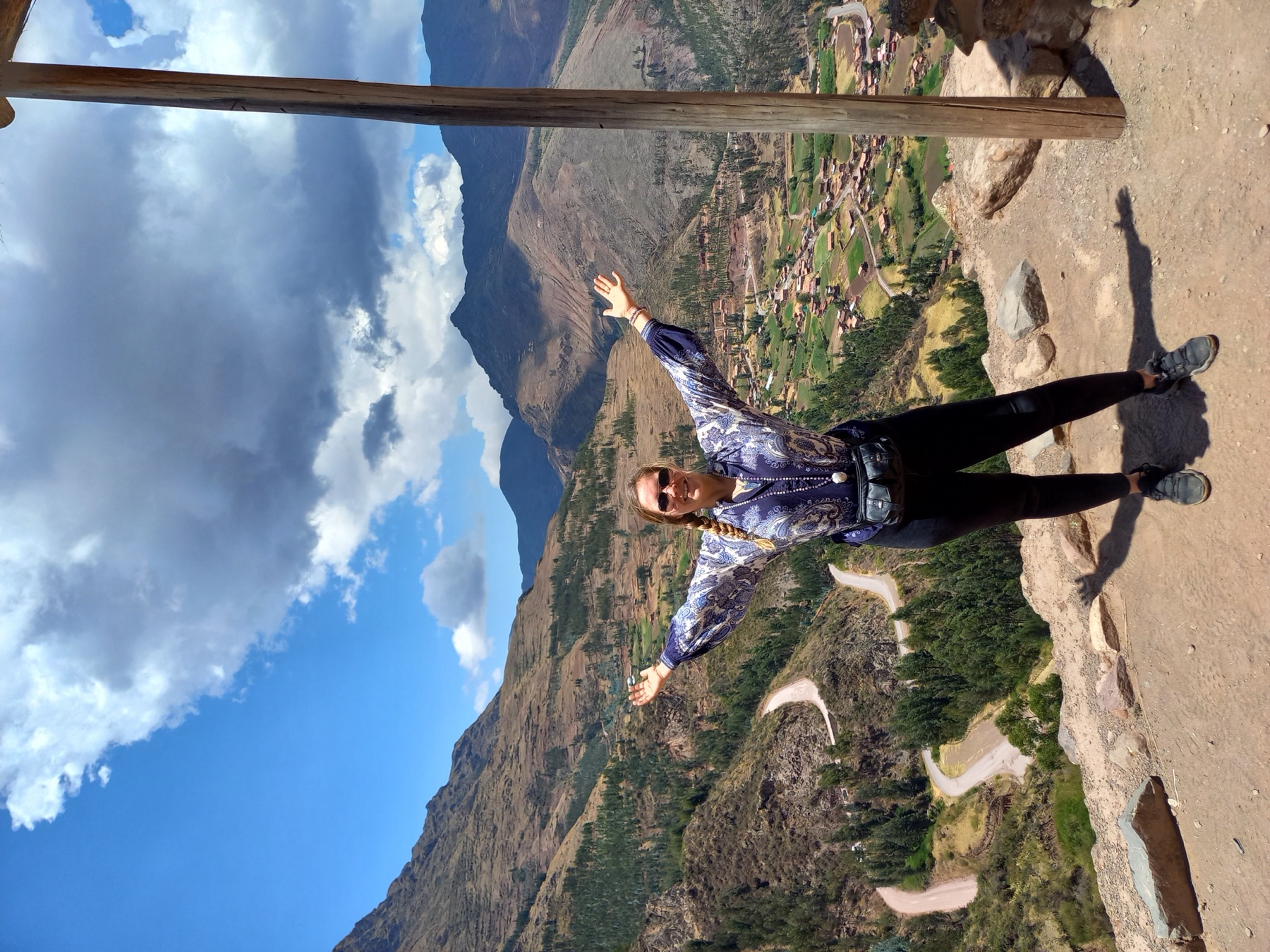 Jade with her arms wide open above a valley in the Andes